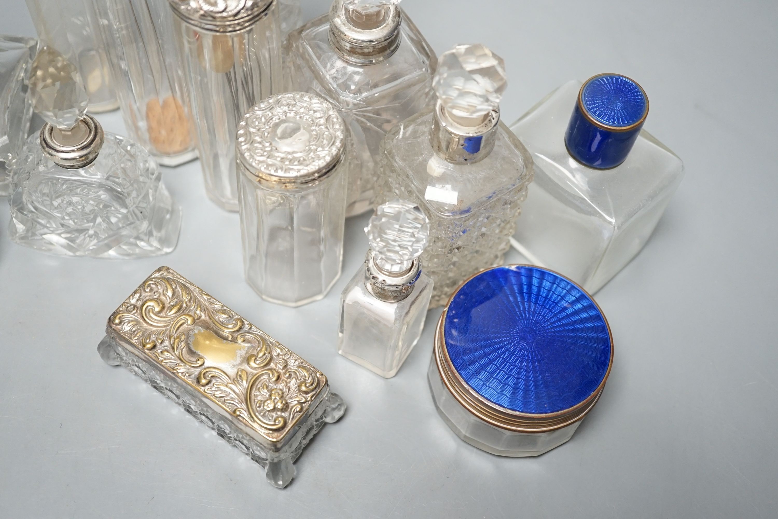 A collection of assorted mainly silver-capped scent bottles and toilet jars, etc. including two gilt metal and enamel.